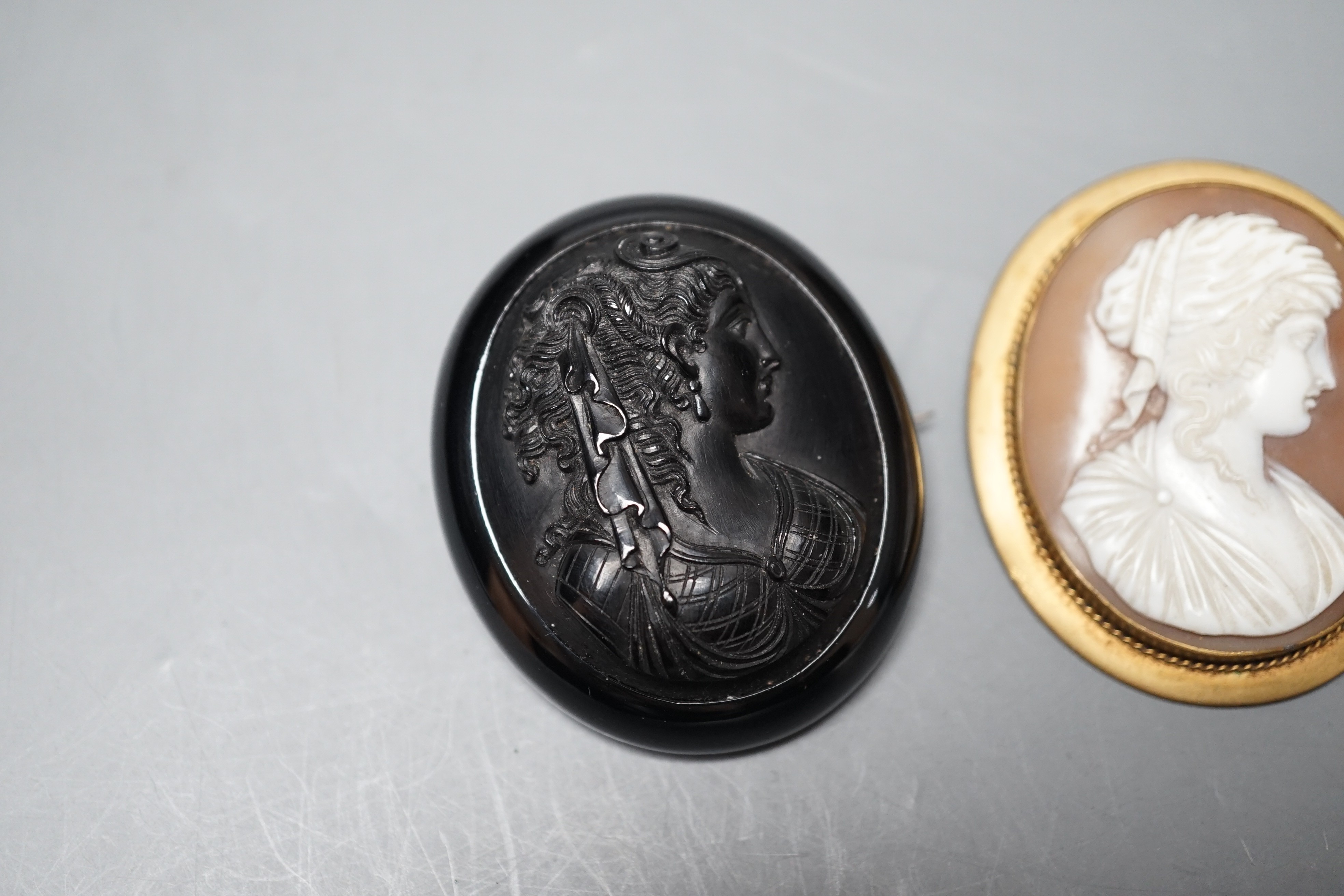 A good quality unmounted oval cameo shell, carved with the bust of a Roman soldier to sinister, 56mm, in Antrobus box, together with two cameo set brooches.